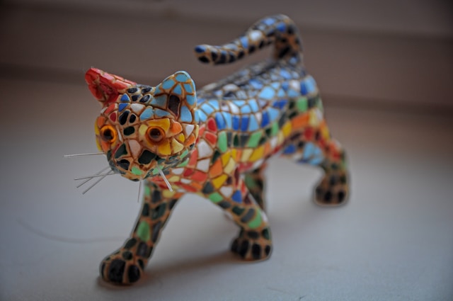 En skulptur av en liten katt dekket med mosaikk kunst